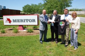 Photo of check presentation with Meritor company sign in the background.