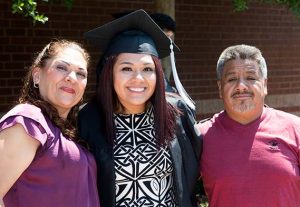 A smiling WPCC female graduate with her parents at graduation