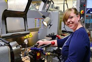 Photo of a female WPCC student working with a lathe