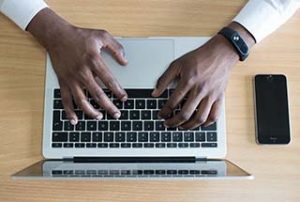 A pair of hands types on a laptop computer keyboard seen from above