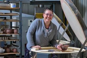 Photo of WPCC student loading pottery into a kiln for firing