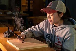 Photo of a WPCC student performing woodburning in the wood lab