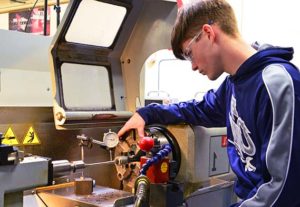Photo of a WPCC male student operating a machining press