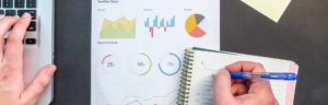 PHoto of someone working at a computer with business charts scattered around