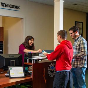 Photo of the WPCC student services welcome desk with the receptionist working with two potential students