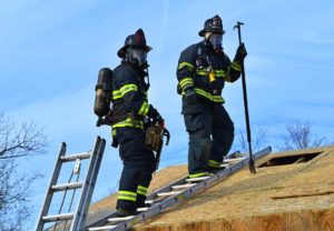 Two firefighters who are training pose for a photo on the roof of a building
