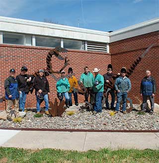 WPCC welding students pose with the new dinosaur garden they created next to Breeden Hall on the WPCC Main Campus