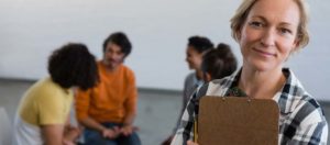 Photo of a Middle-Aged Woman smiling at the camera with other students out of focus behind her