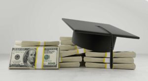 A graduation hat sits atop a pile of money