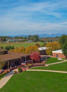 A view of the grassy commons on the WPCC main campus in fall with Table Rock and Hawksbill Mountains in the background