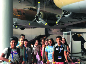 Students standing underneath airplanes at the WWII Museum in New Orleans.