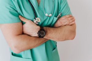 Image of a healthcare worker crossing their arms in teal scrubs wearing a stethoscope