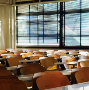 Image of desks in a classroom with windows and black blinds