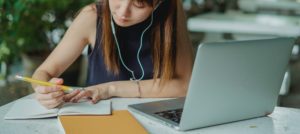Image of a female student studying taking notes and with a laptop