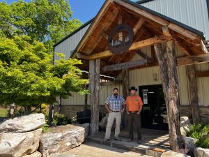 Image of 2 men standing in front of the entrance of a building.