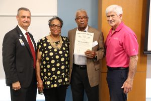 Image of 4 people with a trustee receiving the order of the long leaf pine.