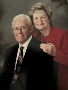 Image of Roy and Jan Walters smiling in front of a dark grey background.