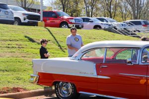 An older adult and young child looking at a vintage car.