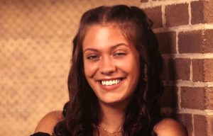 Image of Emily Powell, scholarship recipient smiling for a photo in front of a brick building.