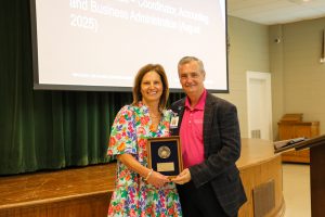 Image of 2 people smiling for a photo holding a plaque