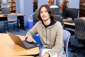 Student smiling for a photo with a laptop