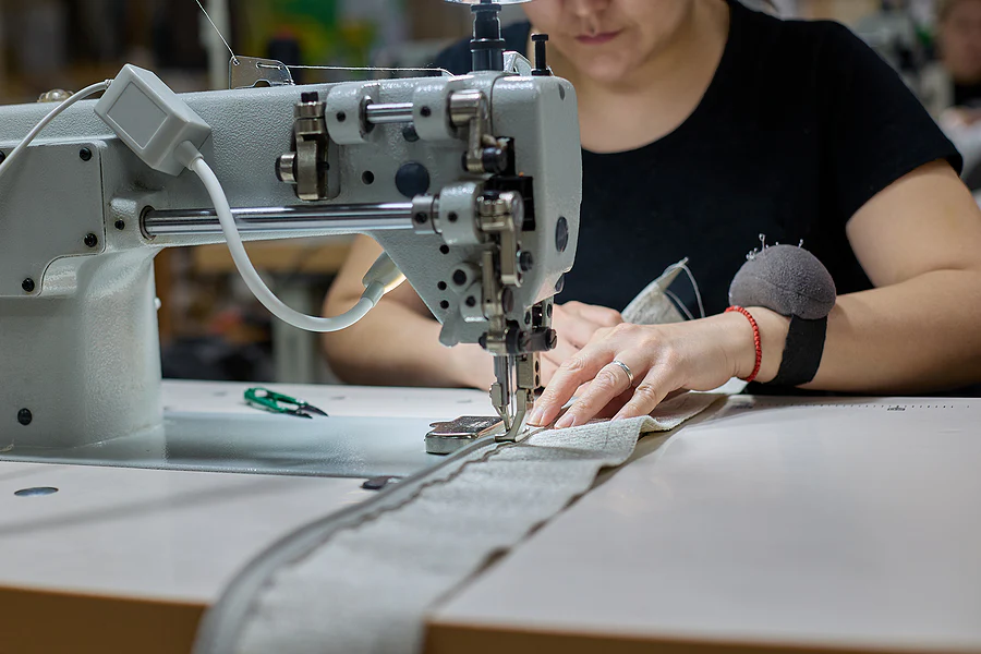 Someone using fabric through a sewing machine