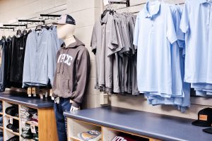 Image of a row of shirts in the WPCC bookstore. Colors are blue, gray and features a mannequin in the center of the image with a WPCC hoodie and hat.