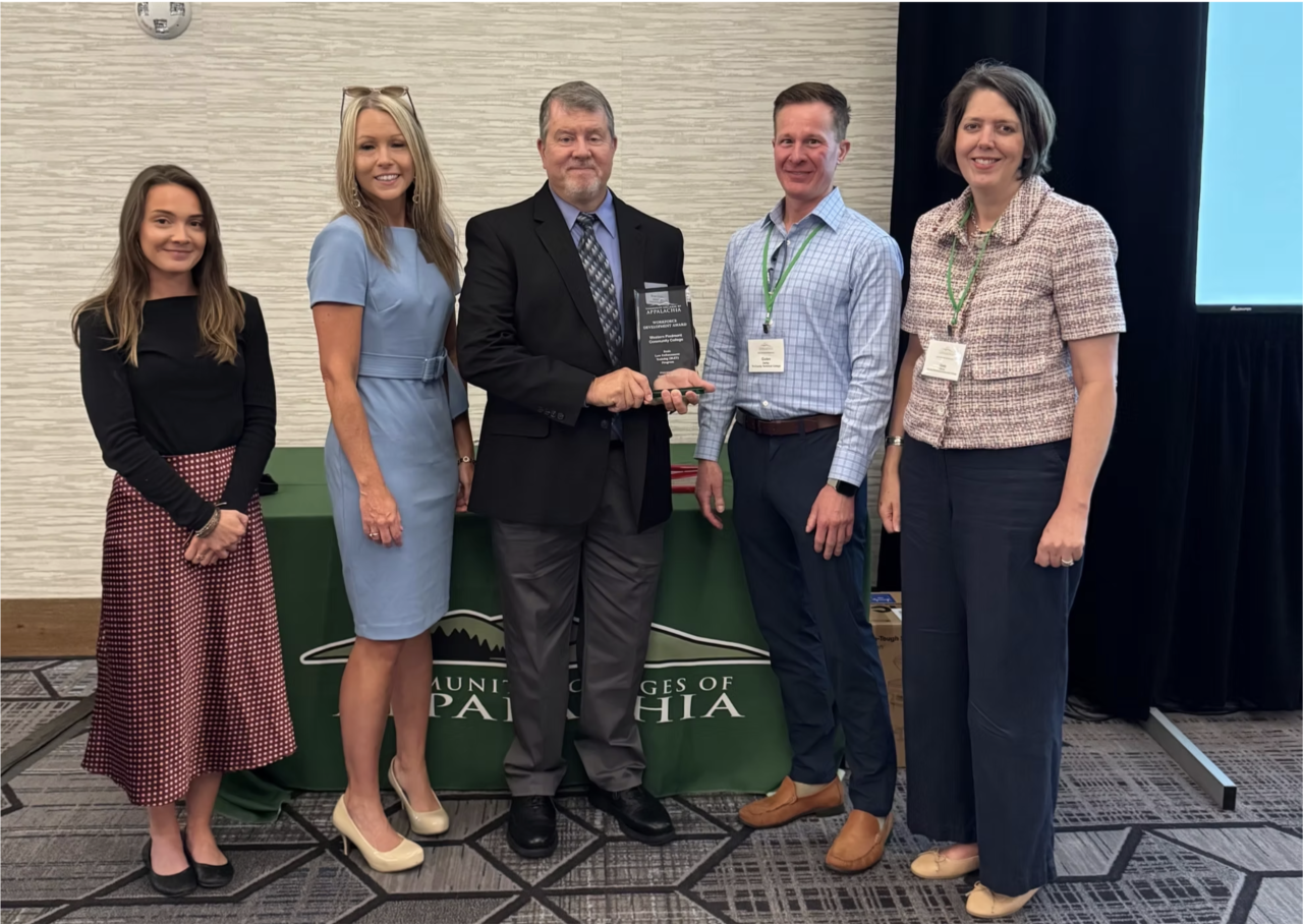 Image of 5 people smiling for a photo with an award